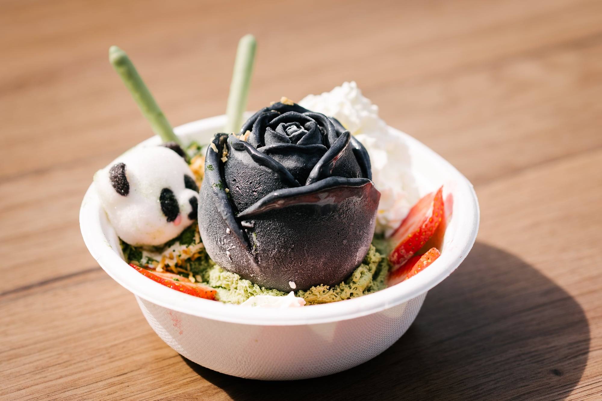 Bowl mit schwarzer Eis-Rose und Panda-Mochi auf einem Holztisch