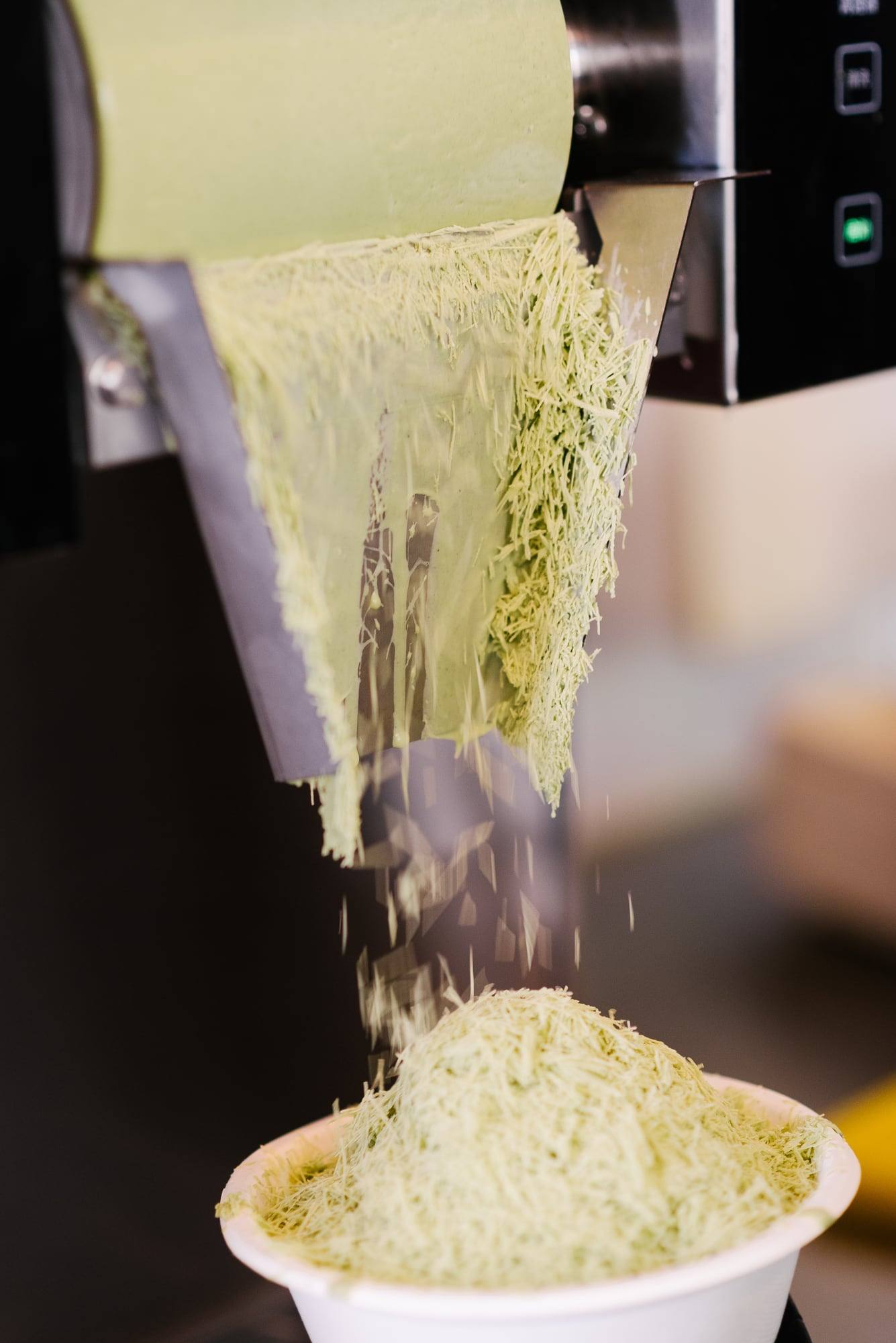 Matcha-Schneeeis fällt aus der Maschine in eine Schale