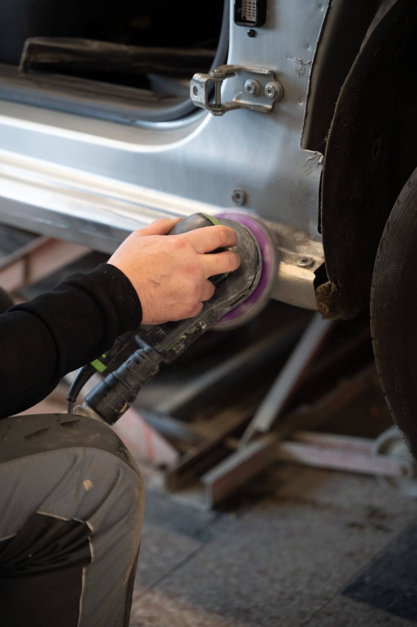 Mechaniker poliert die Karosserie eines Autos in der Werkstatt