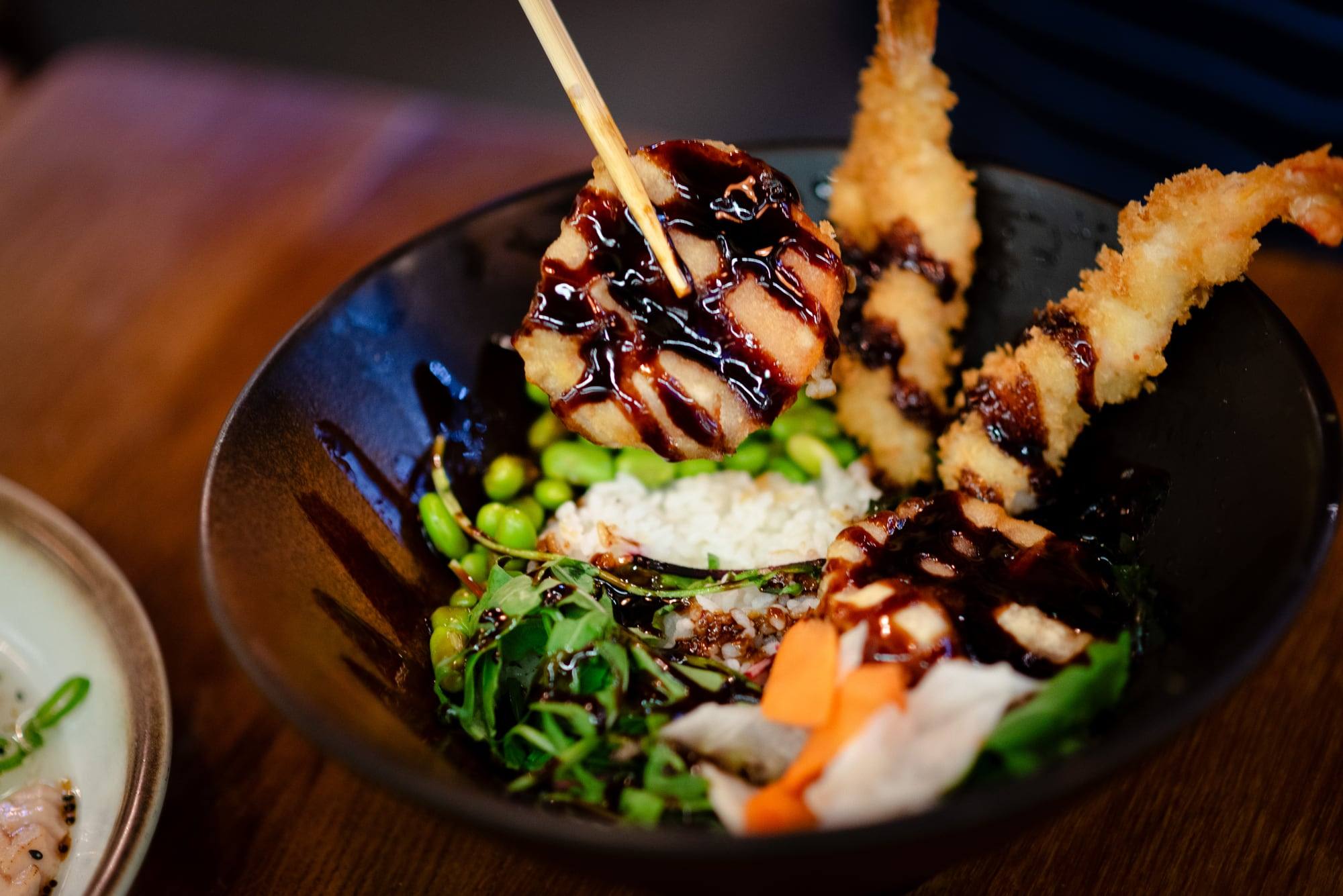Schwarze Bowl mit Tempura-Garnelen, Reis und Edamame