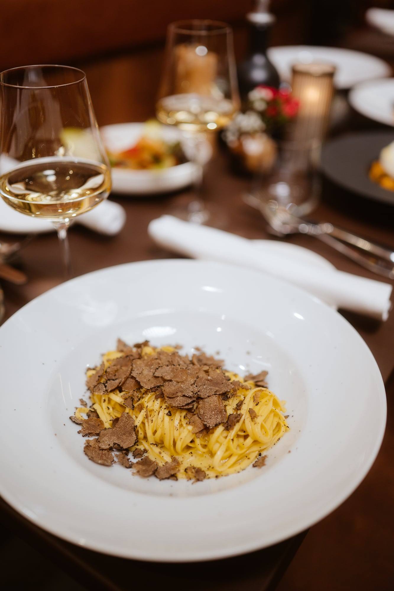 Tagliolini mit Trüffel neben einem Glas Weißwein