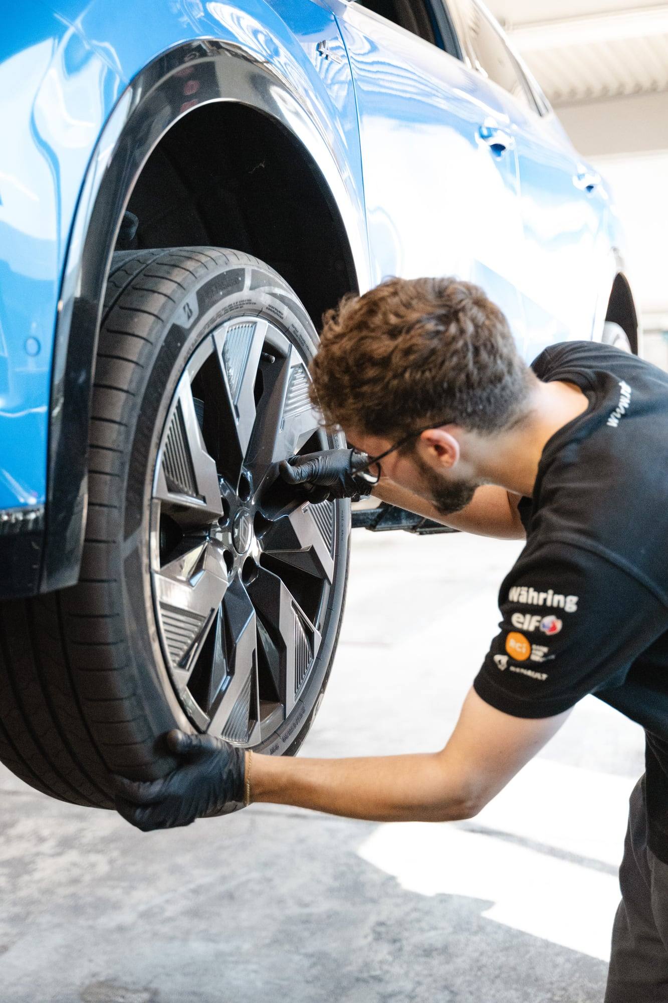 Mechaniker arbeitet an der Felge eines blauen Autos