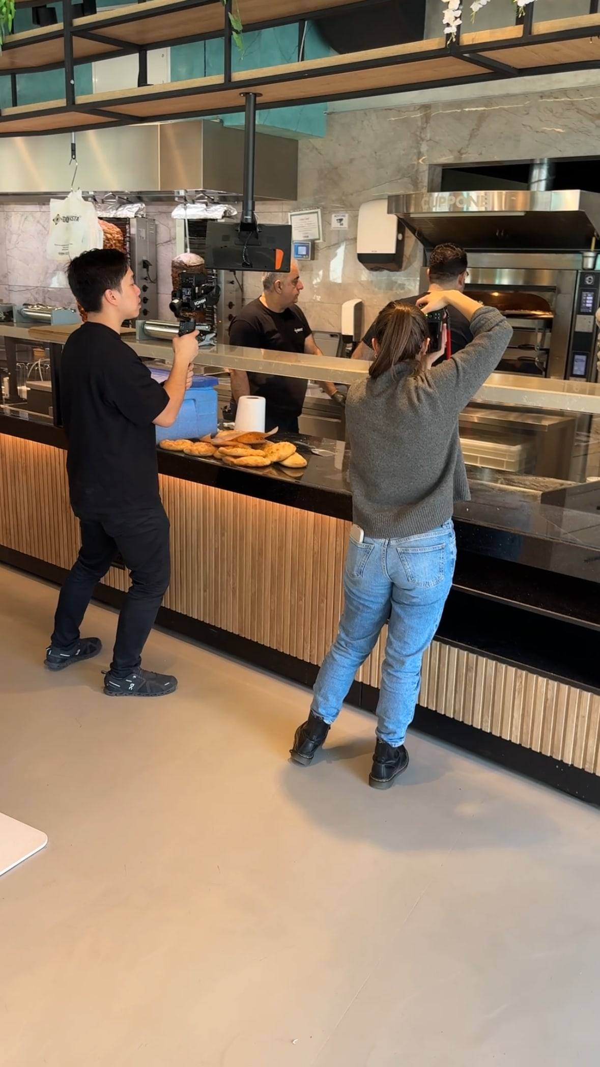Zwei Videografen filmen an der offenen Küche eines Lokals