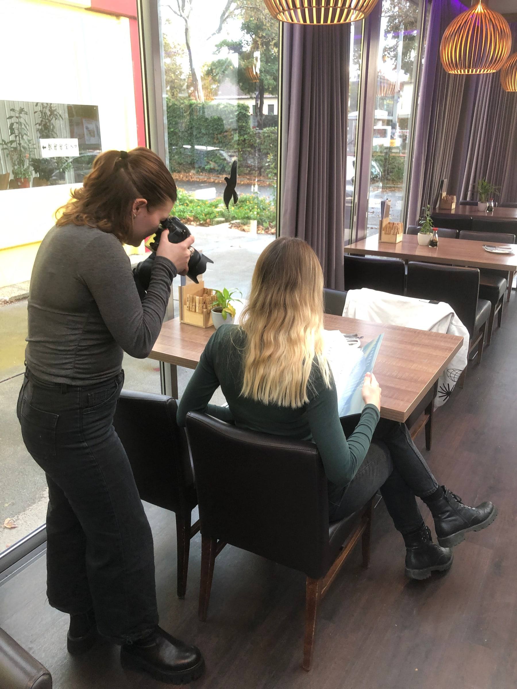 Fotografin fotografiert im Wokhouse einen Gast mit der Speisekarte am Fenstertisch